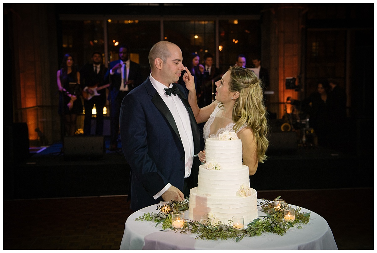 A newly wedded wife putting a cake on her husband's nose during a wedding reception at Guastavinos in New York City. Dress by Ines Di Santo.