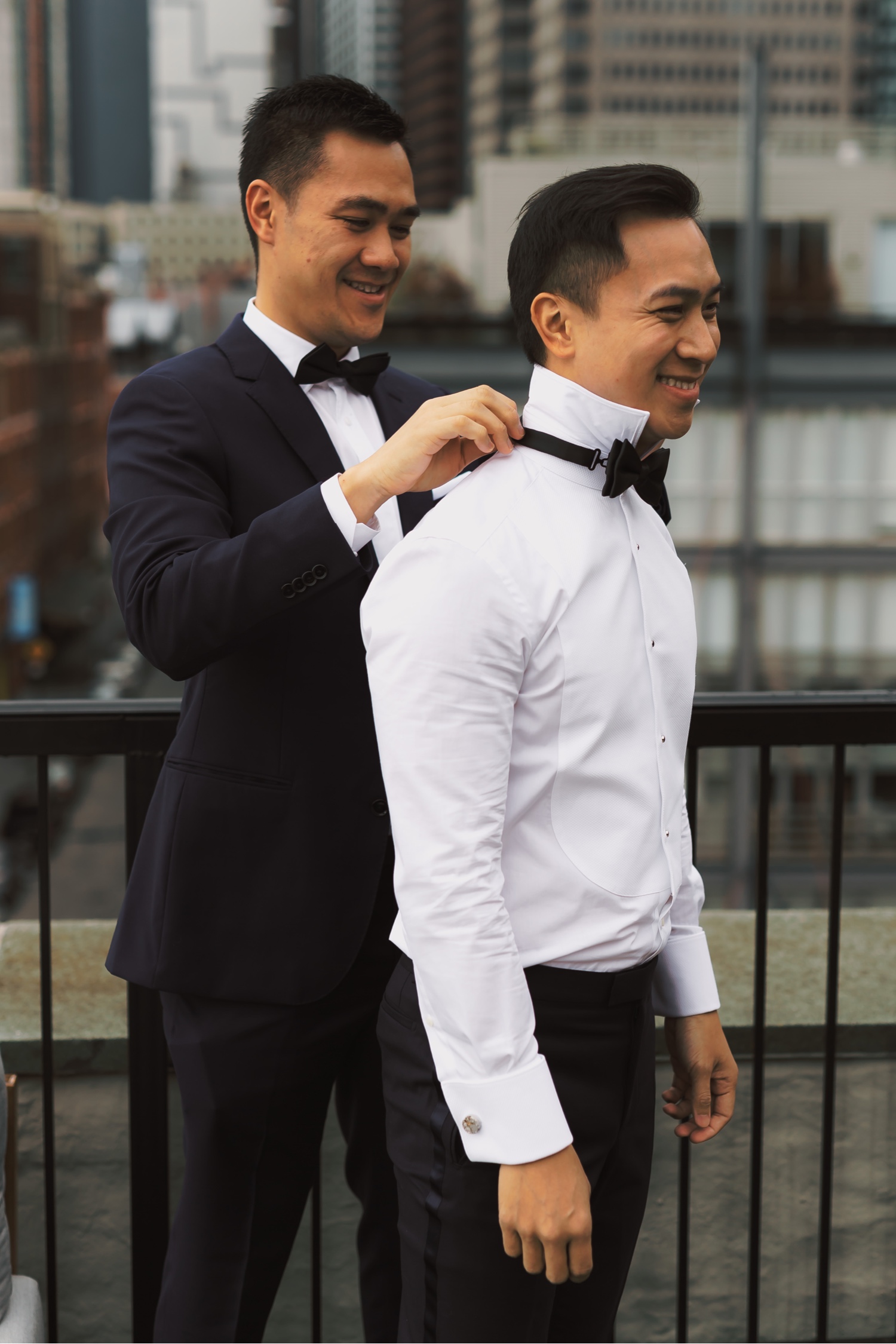 A best man helping a groom to wear a bowtie in a Mr. C Seaport Hotel on a wedding day at Cipriani Wall Street in New York City.
