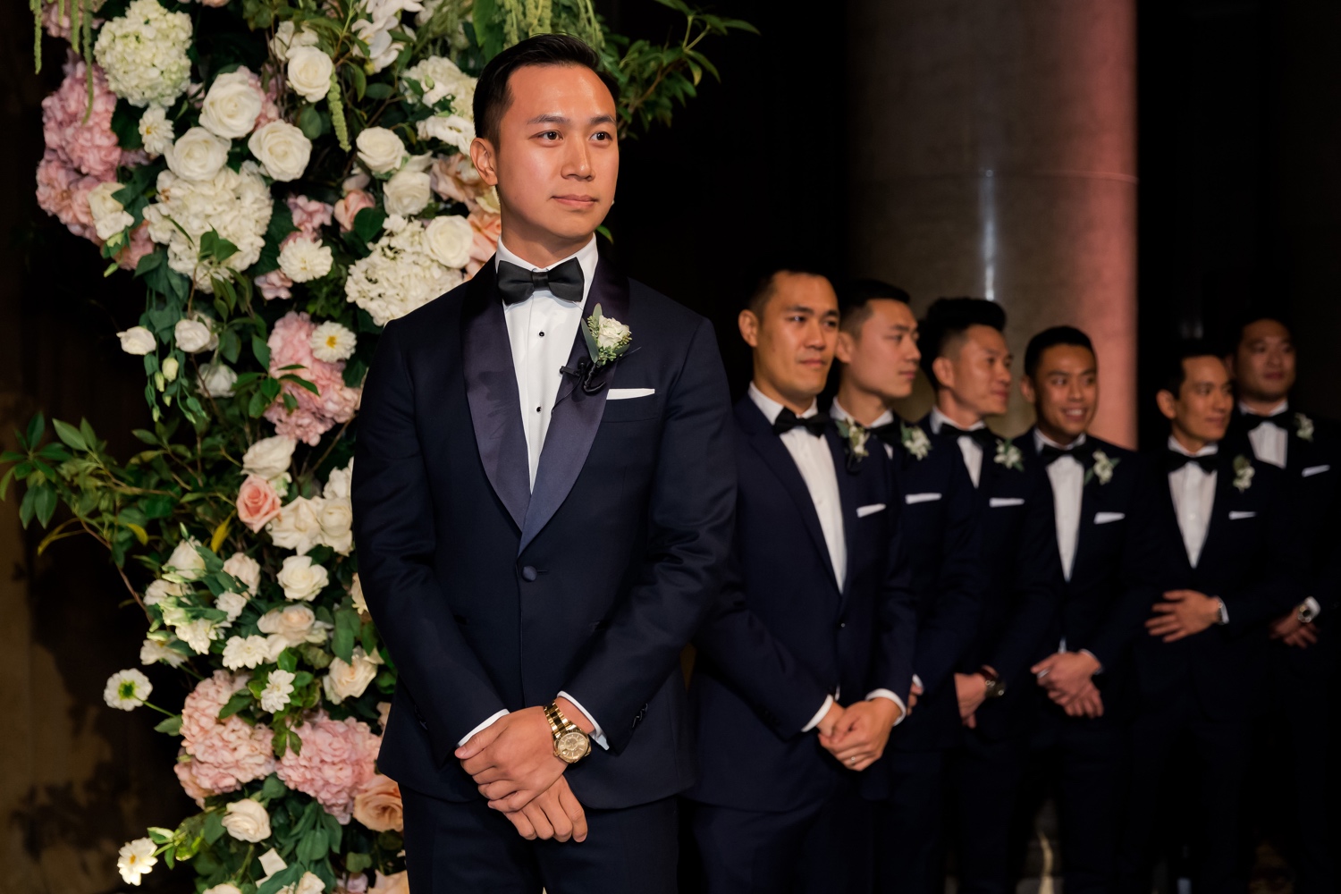 A groom looking at his bride walking in an aisle during a wedding ceremony at Cipriani Wall Street in New York City.