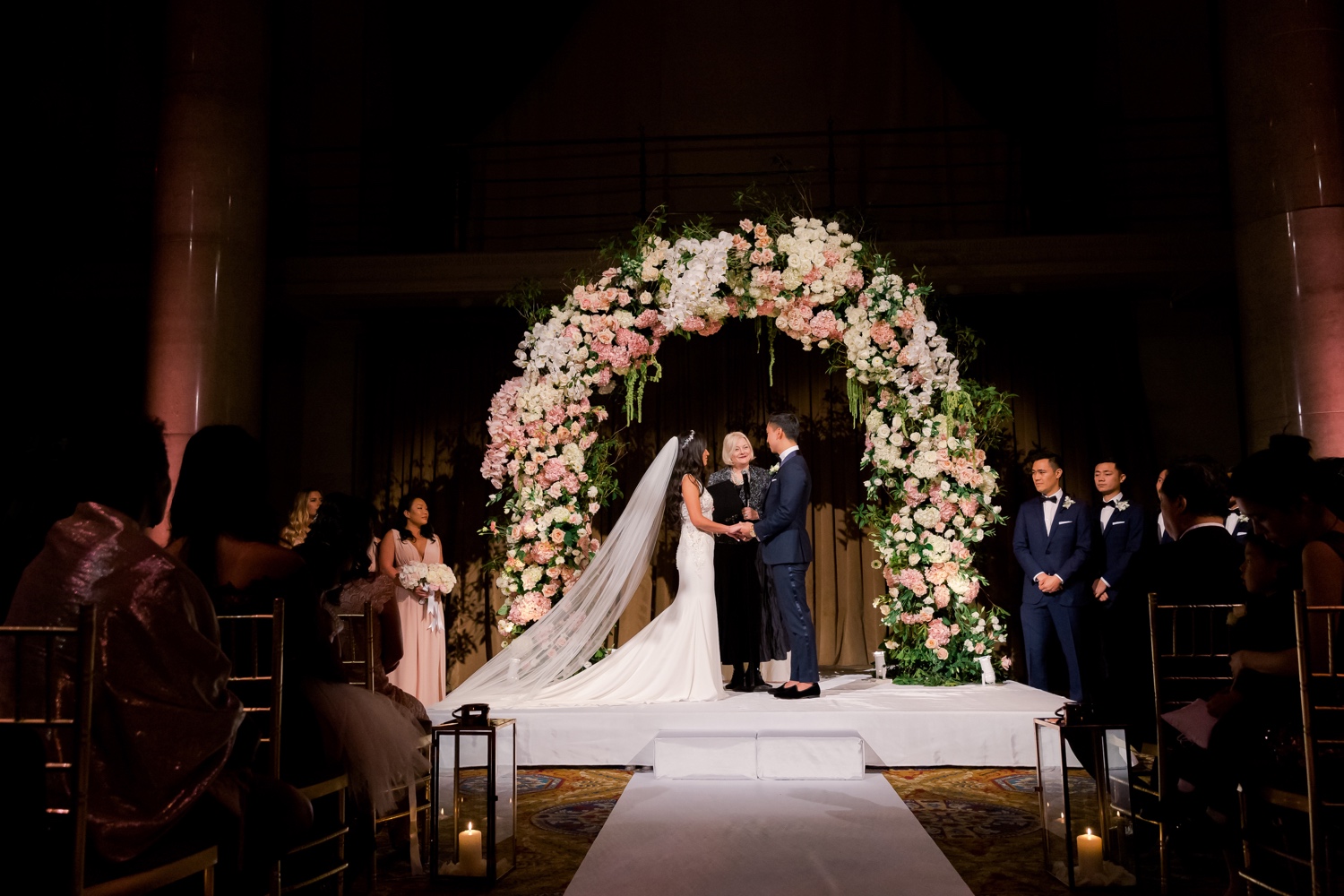 A groom and a bride during a wedding ceremony at Cipriani Wall Street in New York City. Wedding Dress by Pronovias