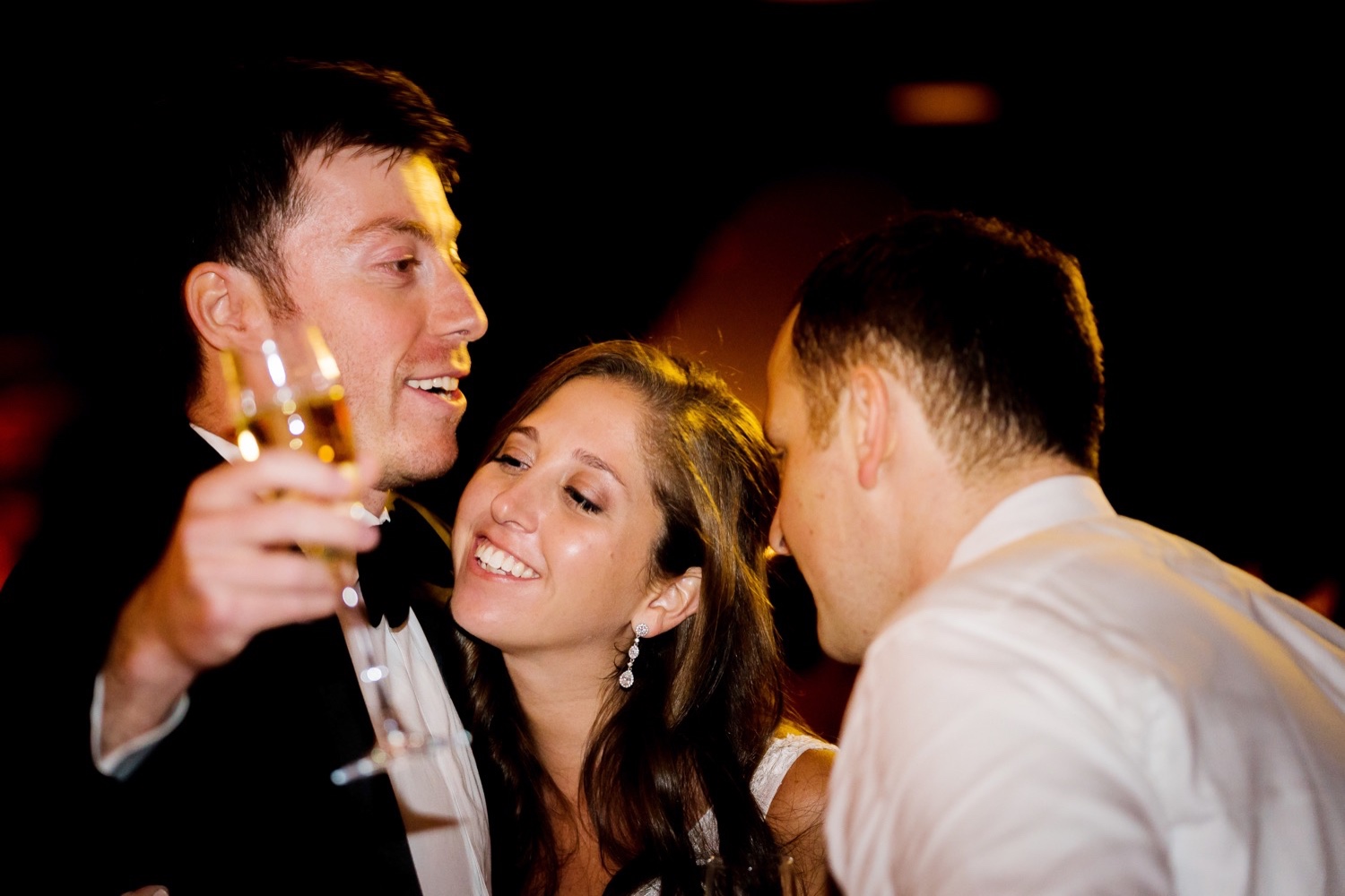A newly wedded couple hugging a best man during a wedding reception at Liberty Warehouse, Brooklyn New York.