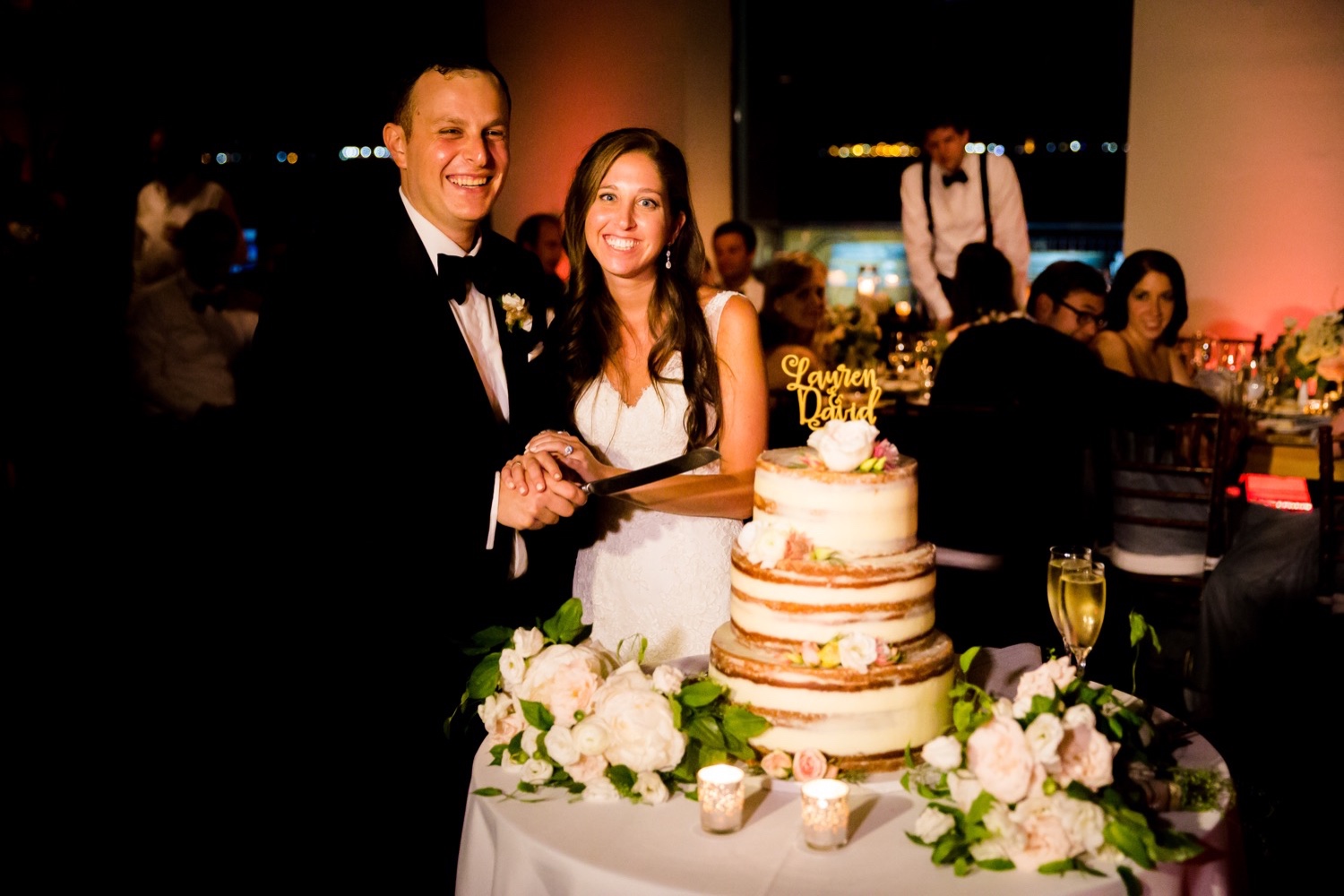 A newly wedded couple cutting their wedding cake during a wedding reception at Liberty Warehouse, Brooklyn New York.