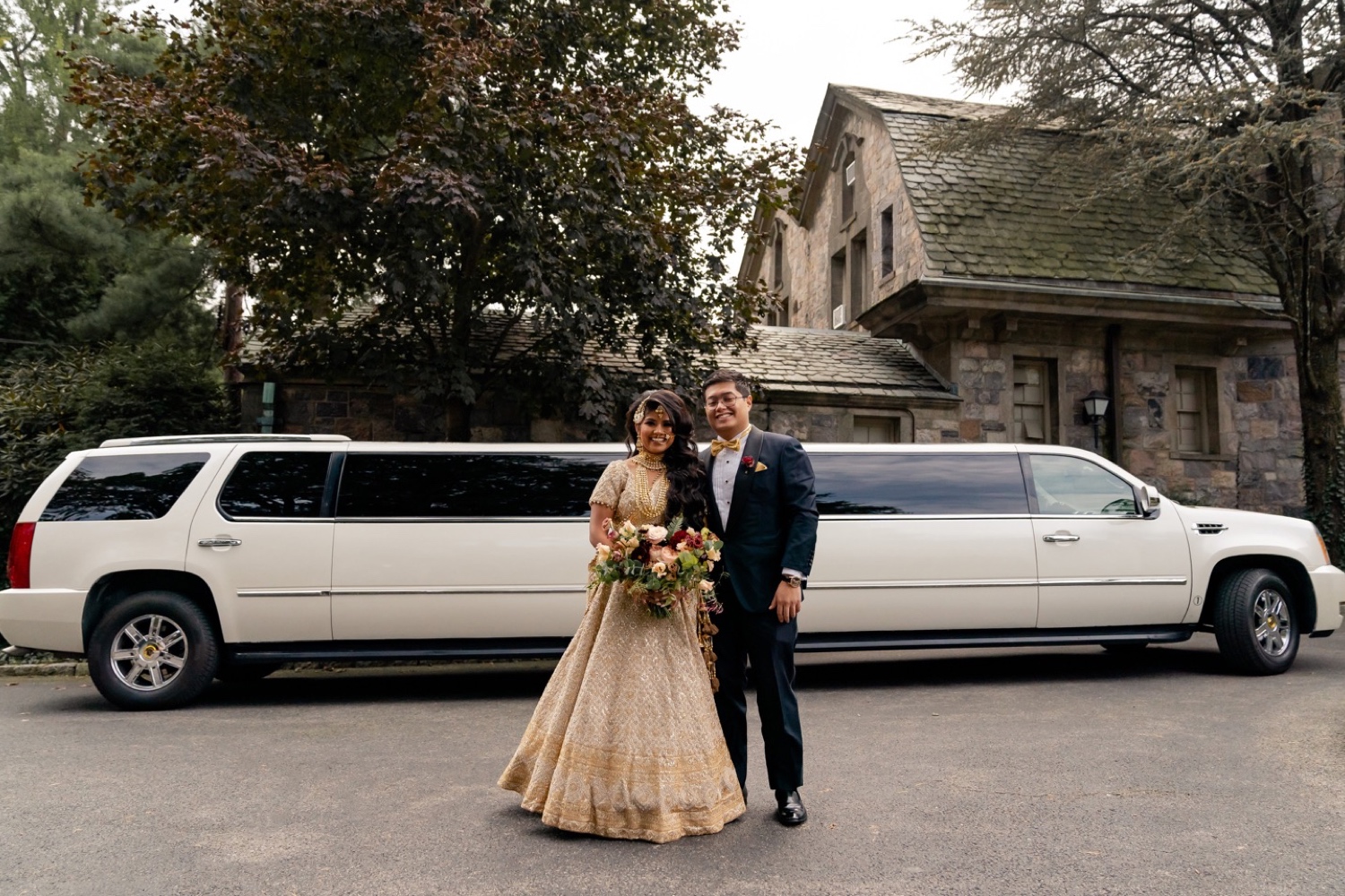 A groom and a bride posing for a picture in front of Tappan Hill Mansion.