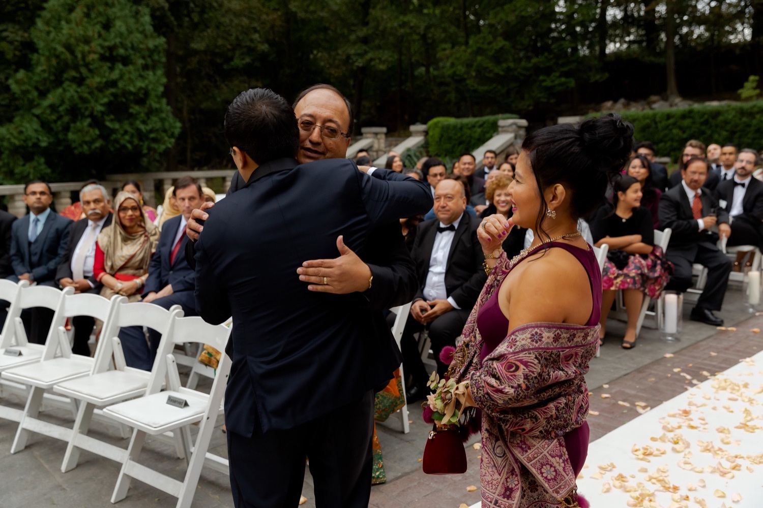 A groom hugging his father during a ceremony at the Tappan Hill Mansion.