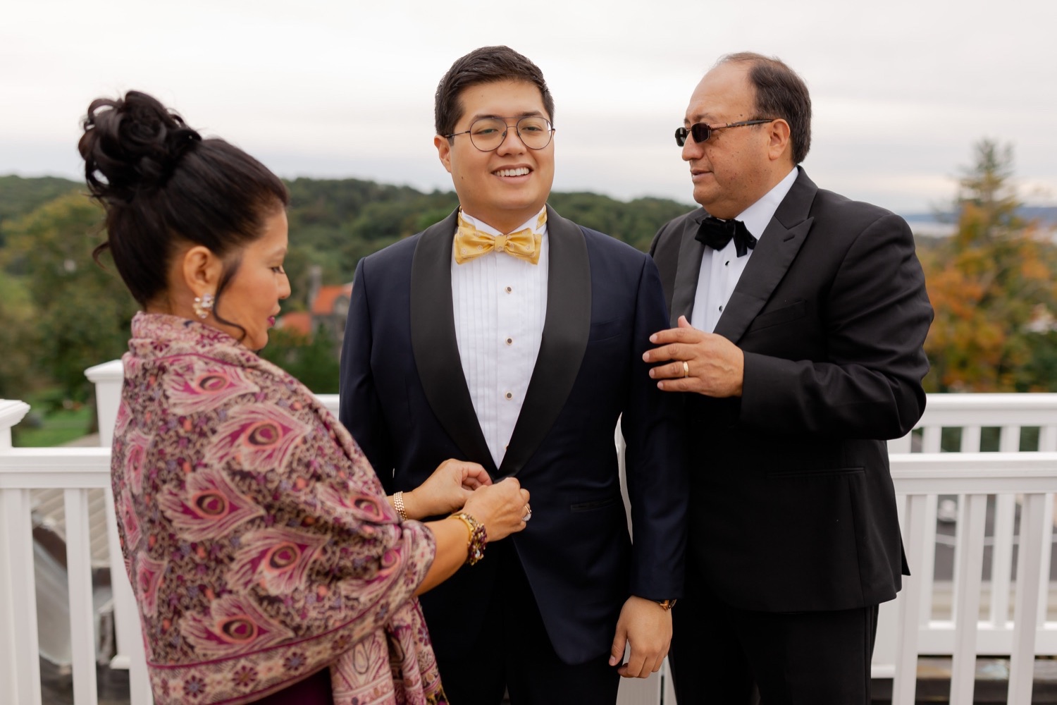 A groom wearing his wedding suit with a help from his family.