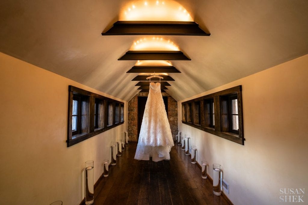 wedding dress hanging in the hallway of the haybarn of blue hill stone barns