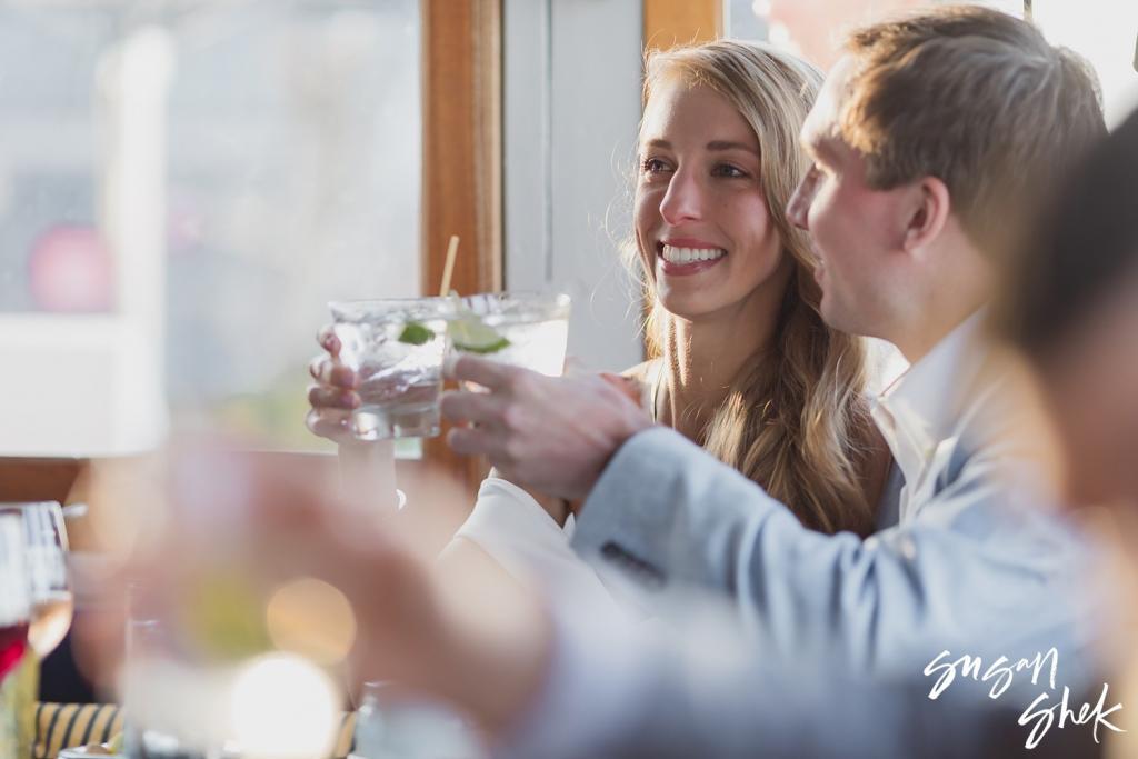 Friends raising cocktails in a toast at a harborside restaurant