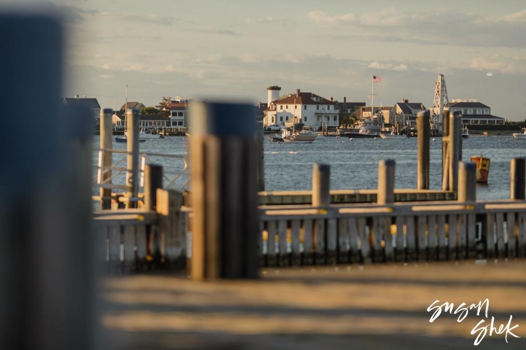 Nantucket waterfront buildings seen past the dock pilings in late afternoon light