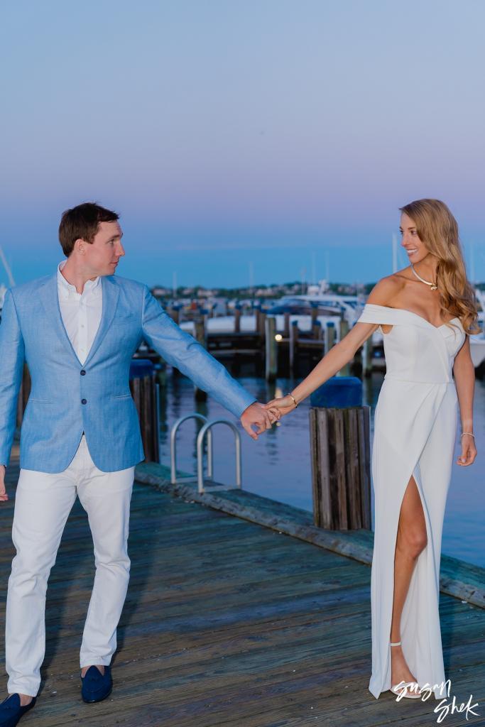 Couple reaching for each other's hands on the dock at twilight
