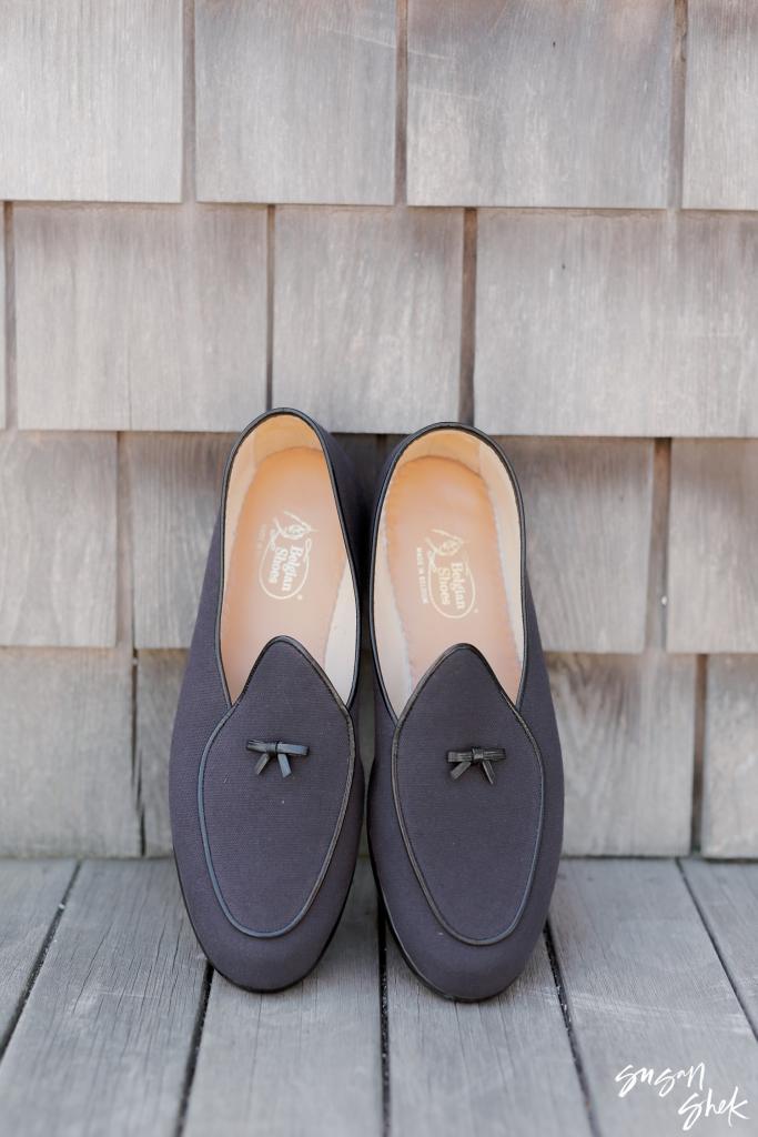 Groom's dark velvet loafers against weathered cedar shingles