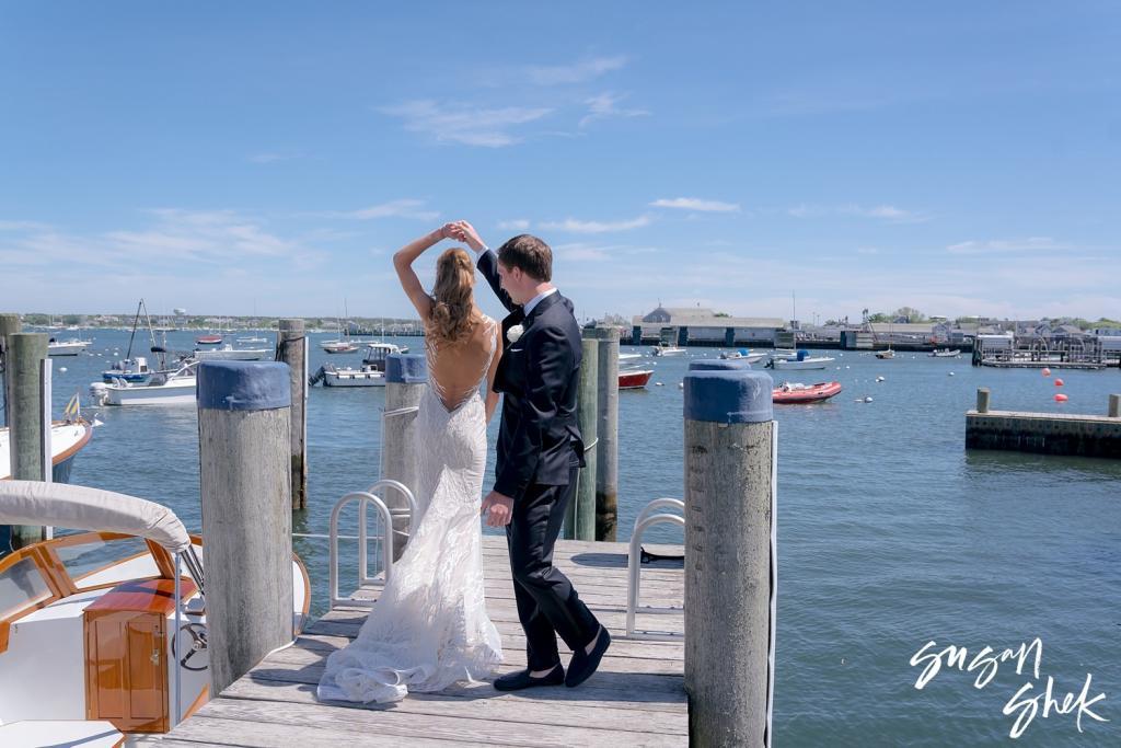 Groom twirling the bride on the dock beside a wooden boat