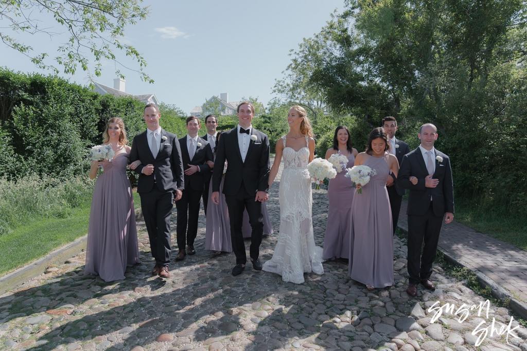 Wedding party walking arm in arm along a country lane