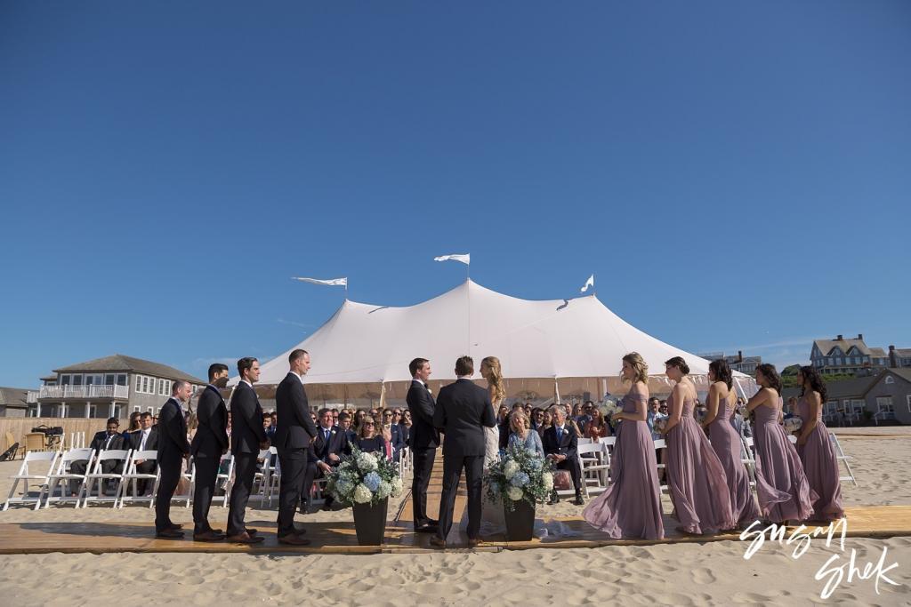 Wedding party standing at the beach ceremony on Galley Beach, with a white sailcloth tent behind them