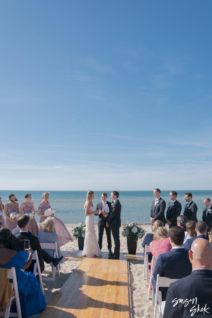 Beach ceremony seen from the back of the aisle with the ocean behind the couple