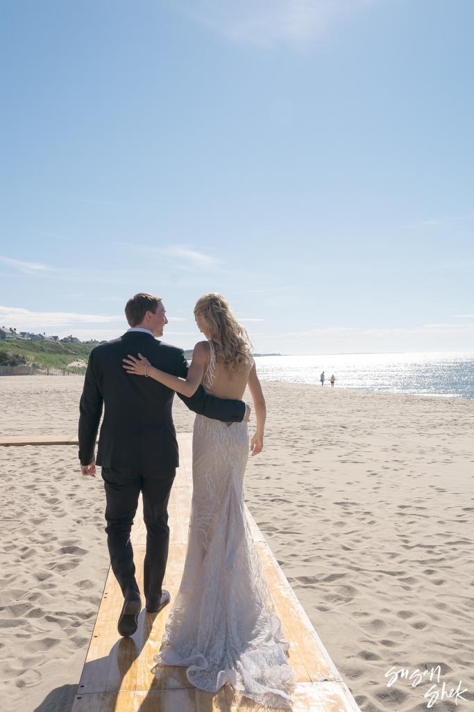Bride and groom walking away together down the beach after the ceremony