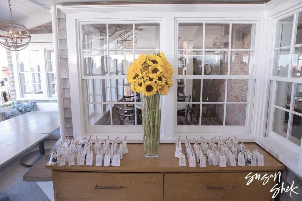 Sunflowers and escort tags set out on a wooden dresser by the windows