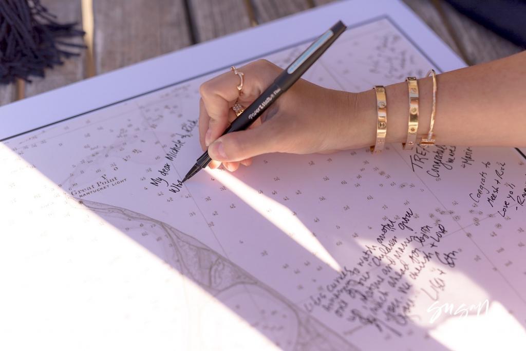 Guest writing a message on a nautical chart used as a guest book