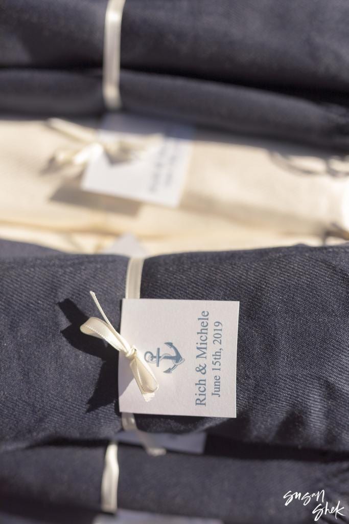 Rolled navy blankets with anchor tags as wedding favors