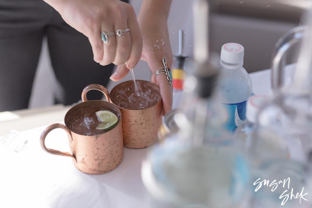 Bartender garnishing copper mugs of Nantucket Mules