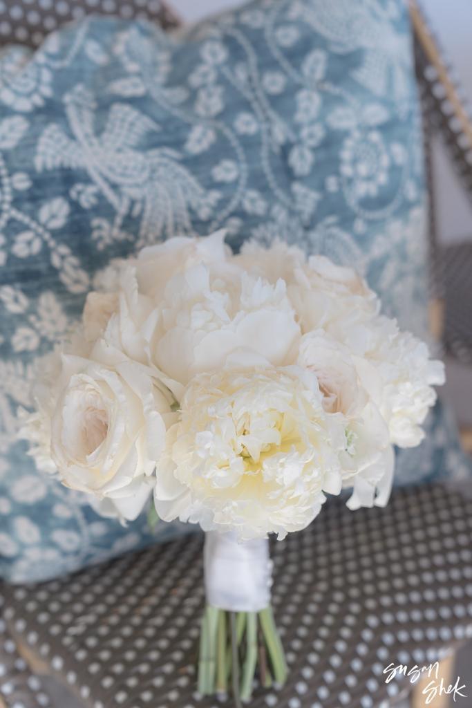 Bride's bouquet of white peonies and roses against a blue patterned cushion