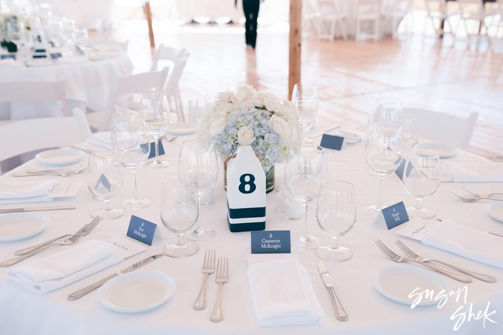 Round reception table with blue hydrangeas and a buoy table number