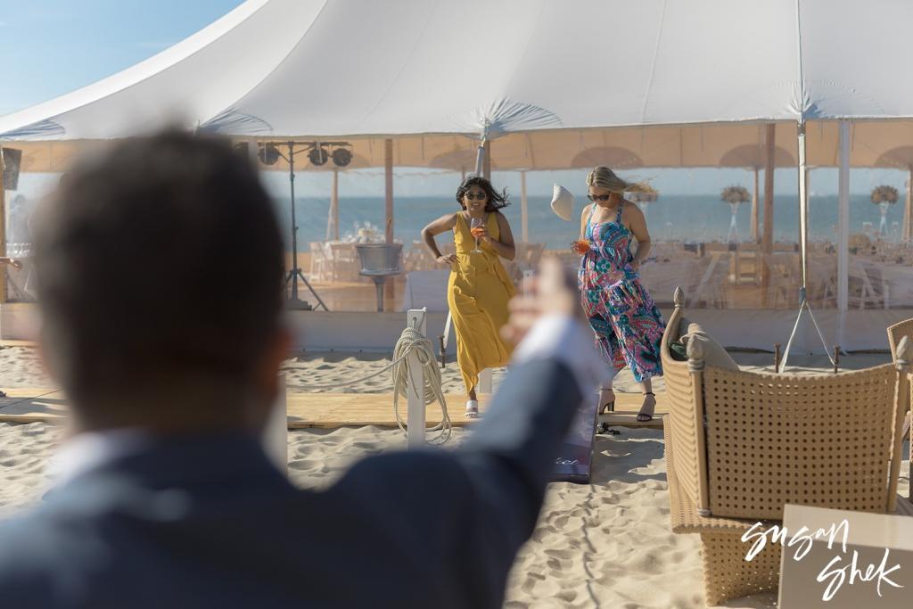 Guests arriving at the beach tent as a guest in a blazer waves to them