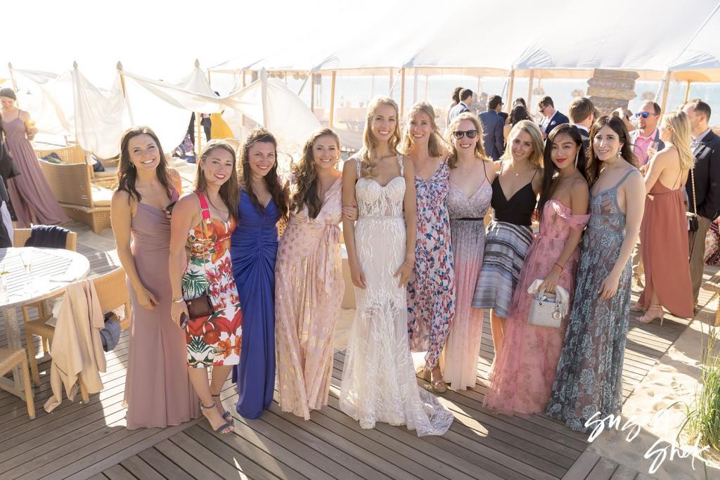 Bride with a group of friends in colorful summer dresses on the deck outside the tent