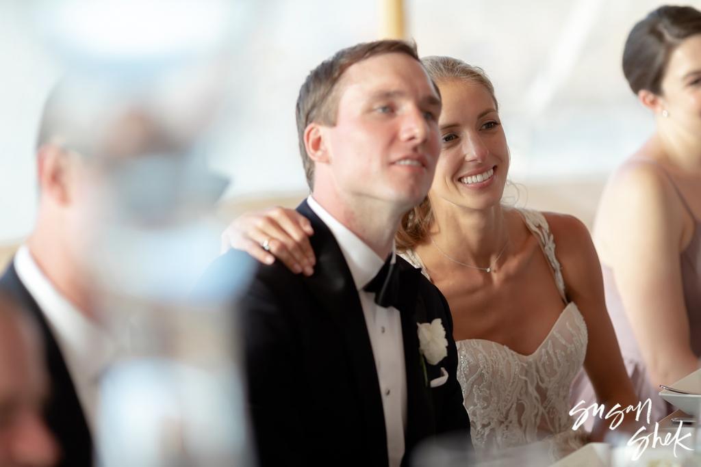 Bride and groom listening to toasts at their table