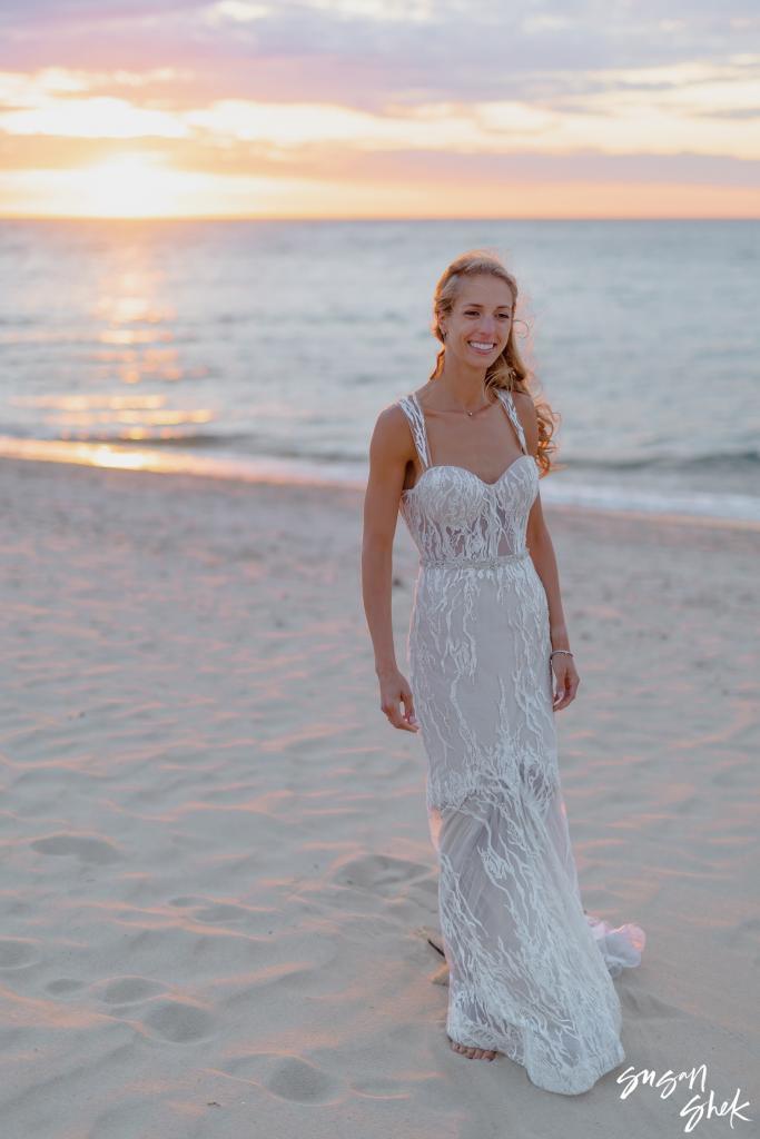 Bride smiling on the sand in soft sunset light