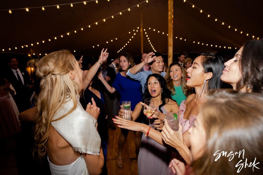 Bride dancing with friends under string lights at night