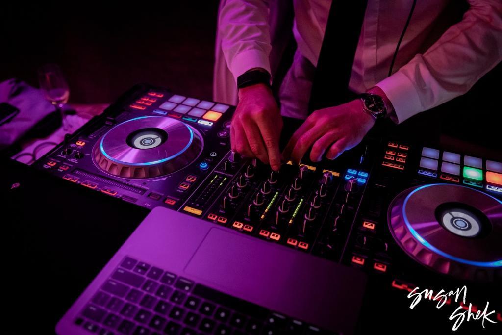 Close view of the DJ's hands on the mixing decks under purple light