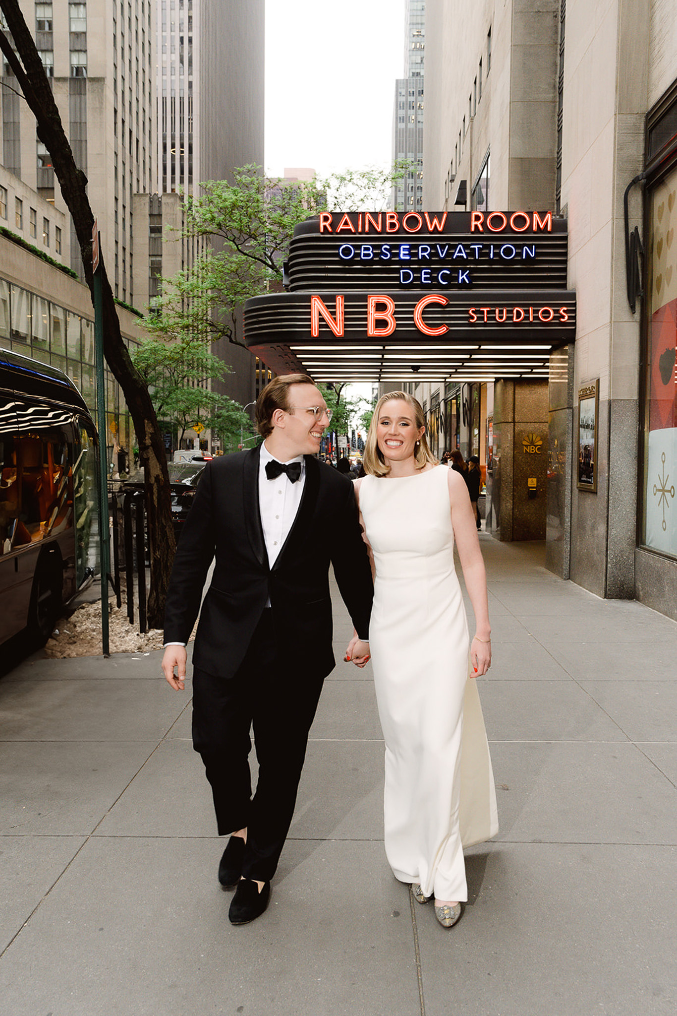 A bride and groom candidly walking outside of Rainbow Room lounge at Rockefeller Center during their elegant NYC wedding celebration