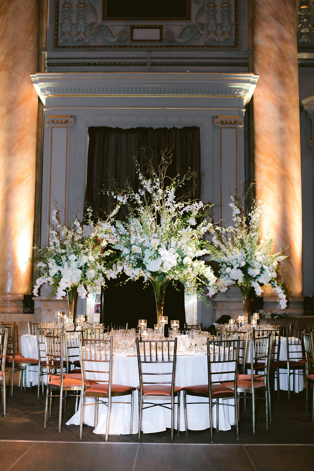 Reception tables decorated with lush white florals beneath the ornate coffered ceiling of Capitale