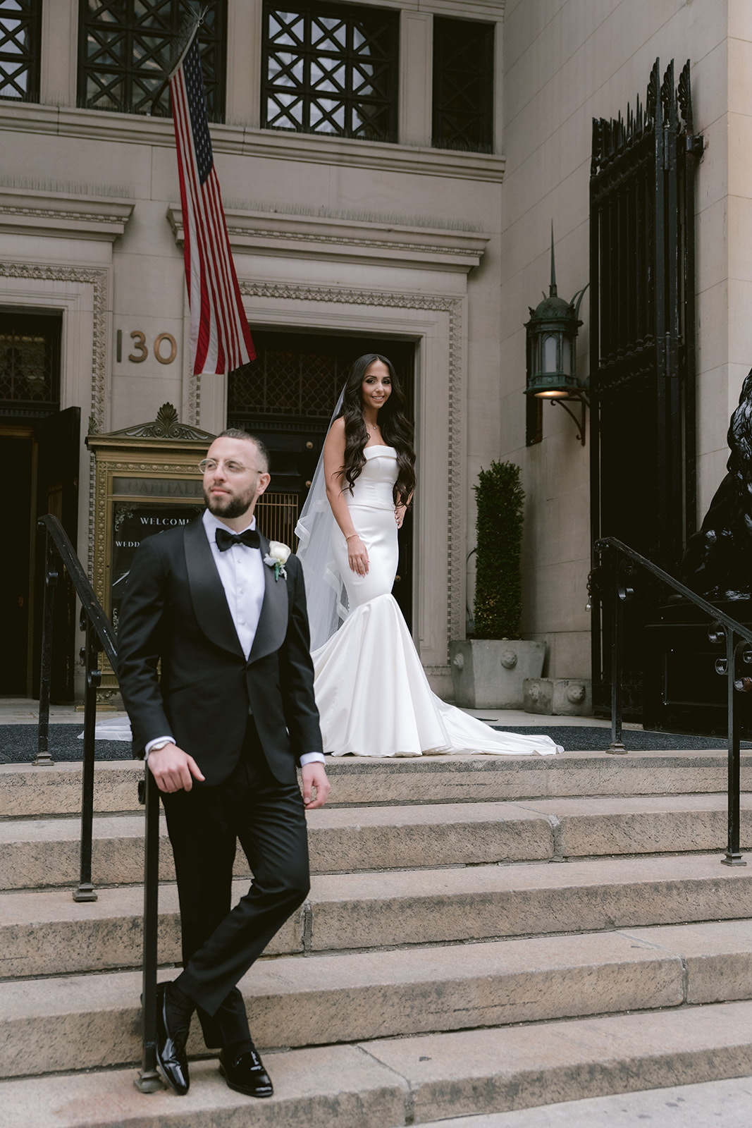 Bride and groom posing on the front steps of Capitale NYC, showcasing the venue’s iconic architecture and arched entryway