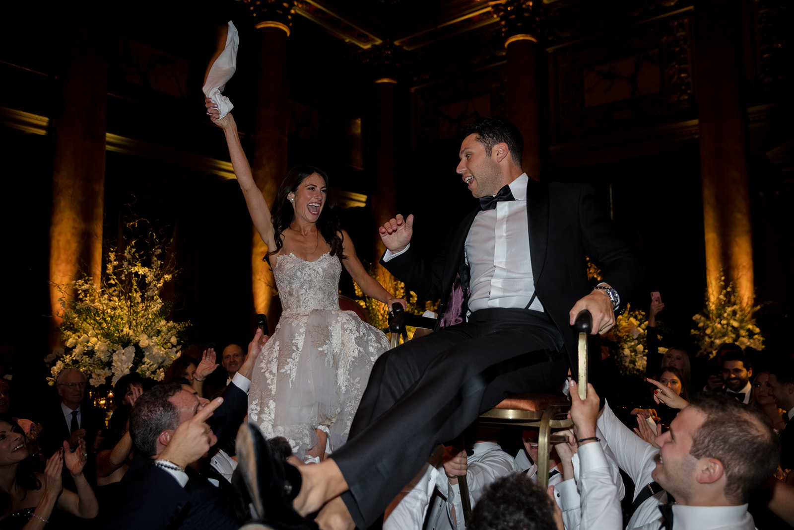 Bride and groom lifted in chairs during the hora celebration inside Capitale, a historic New York City wedding venue.