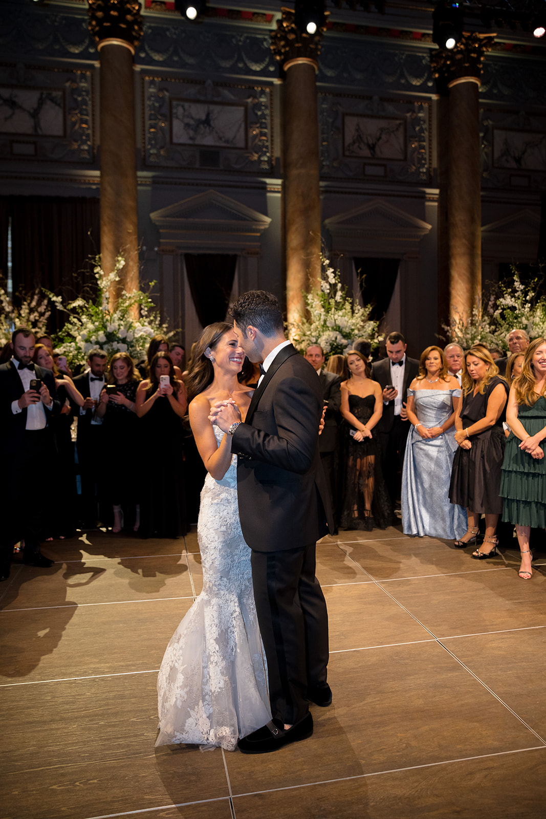 Bride and groom smiling through their first dance surrounded by guests in Capitale’s grand reception hall