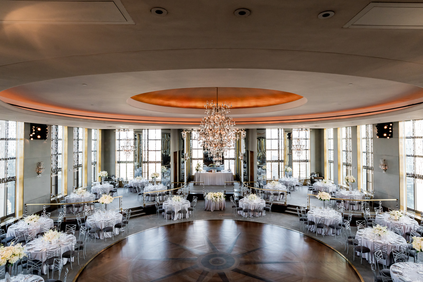 Wide view of the Rainbow Room wedding venue at Rockefeller Center showcasing chandeliers, reception tables, and NYC skyline light