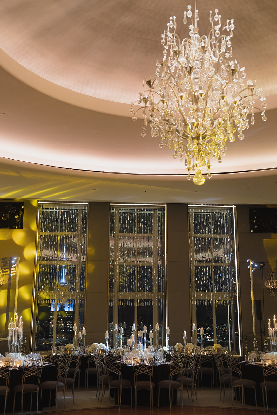 Chandelier and long banquet tables at a luxury wedding overlooking the NYC skyline at Rockefeller Center.