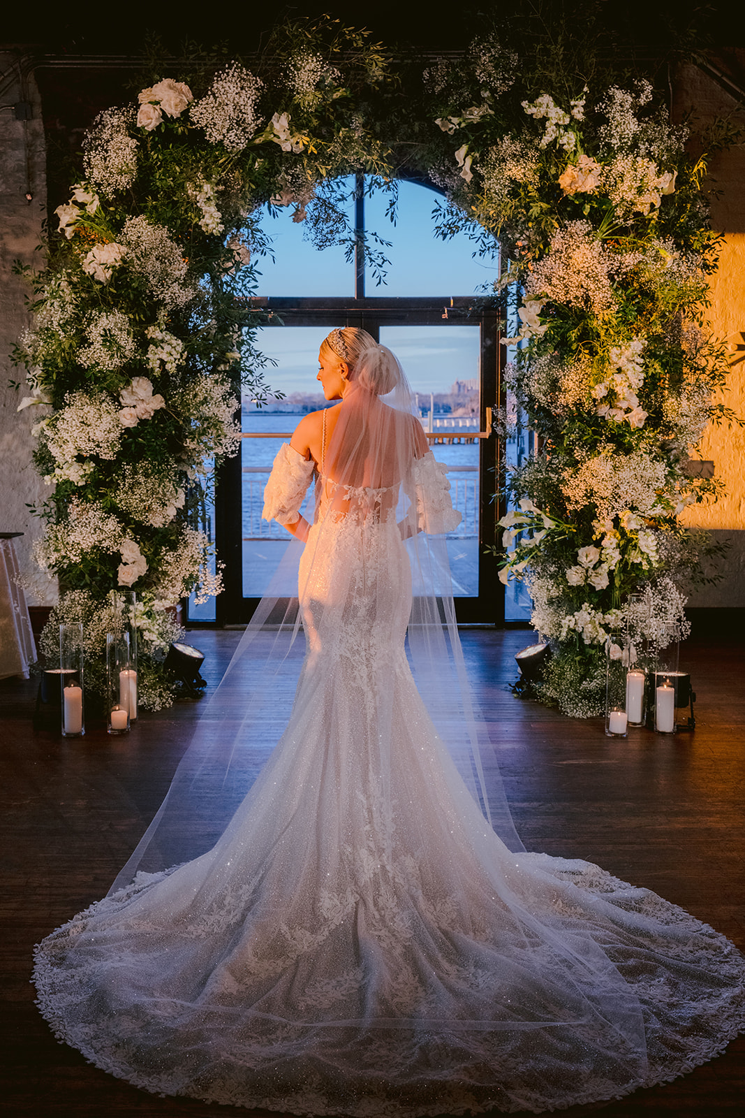 Bride standing beneath floral arch at Liberty Warehouse wedding ceremony