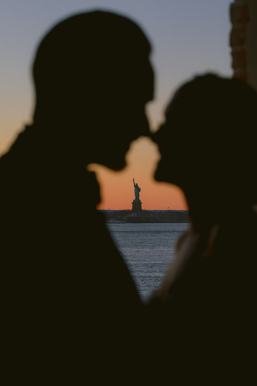 Silhouette of bride and groom with Statue of Liberty at sunset during NYC wedding at Liberty Warehouse in Brooklyn