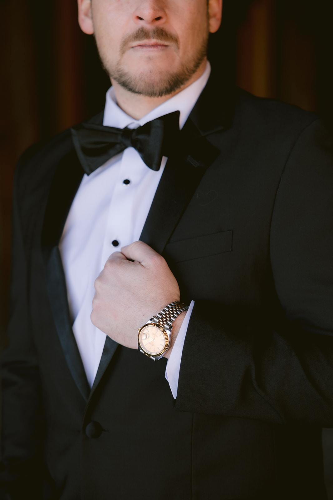 Groom adjusting black tuxedo jacket during Liberty Warehouse wedding getting ready photos