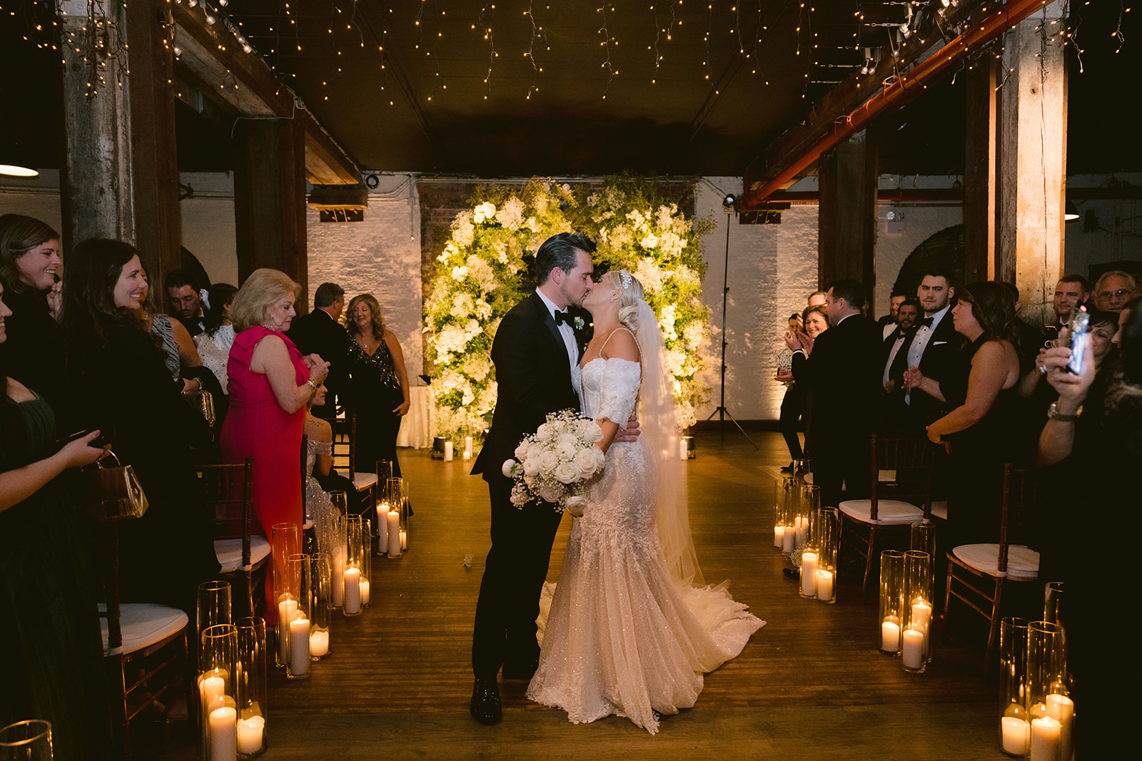 wedding guests cheering as they shared a kiss on their wedding aisle 