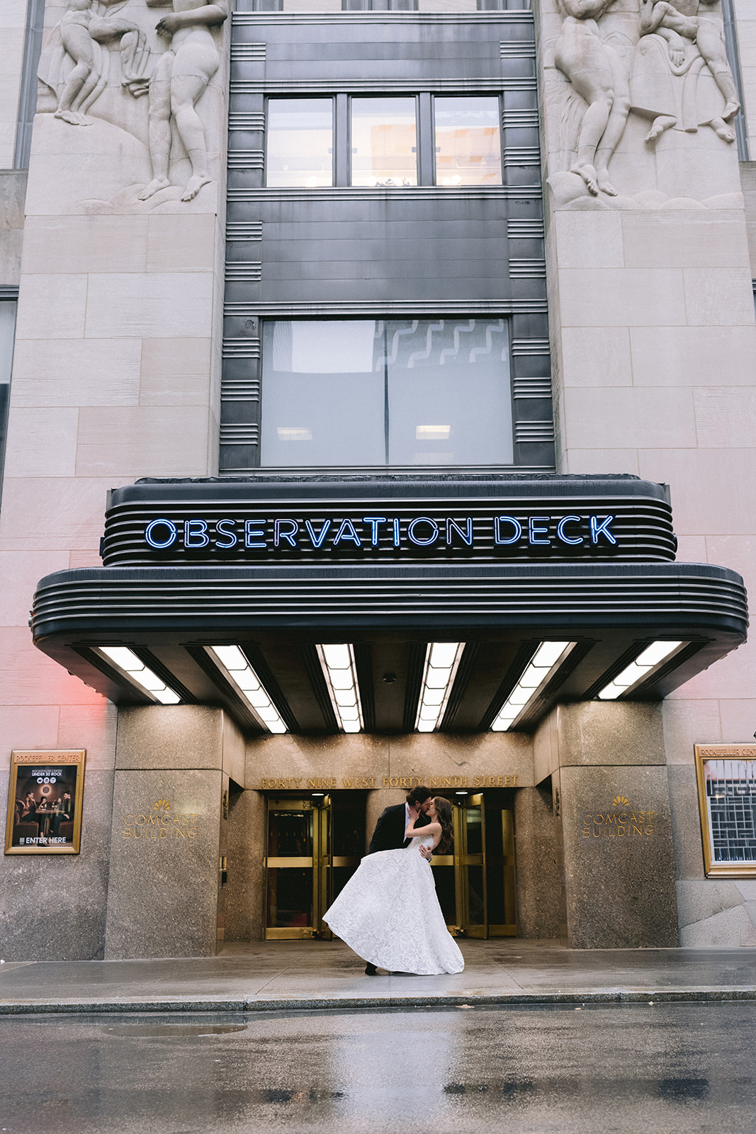 Bride and groom kissing outside Rockefeller Center Observation Deck entrance before their Rainbow Room NYC wedding reception.
