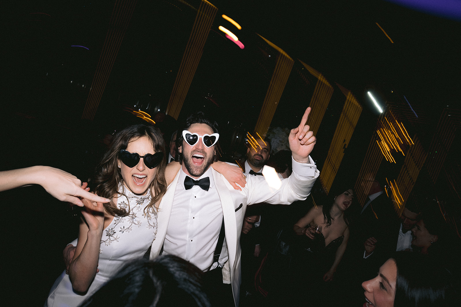 Newlyweds dancing with heart shaped sunglasses on crowded dance floor at NYC wedding reception.