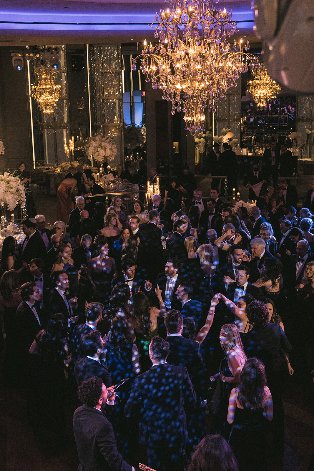 Guests dancing beneath sparkling chandeliers at an upscale Manhattan wedding reception.