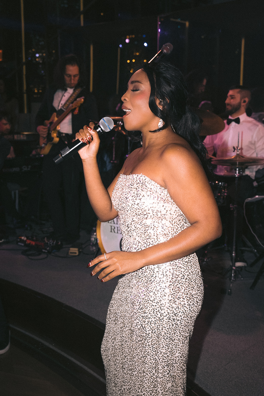 Bride singing with live band on stage during energetic Rainbow Room NYC wedding reception.