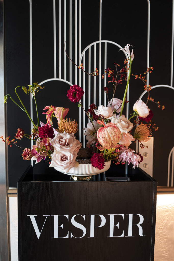 Burgundy wedding floral arrangement on top of a vesper sign
