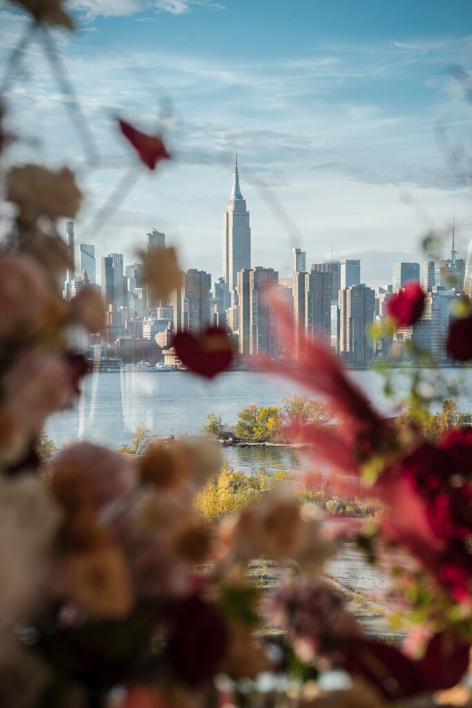 Manhattan skyline view from Vesper Events in Williamsburg Brooklyn framed by soft fall florals overlooking the waterfront.