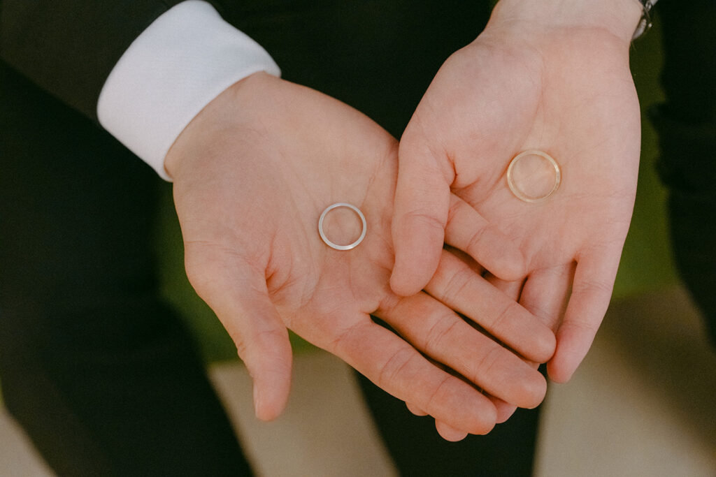 Two wedding bands resting in the grooms' open palms