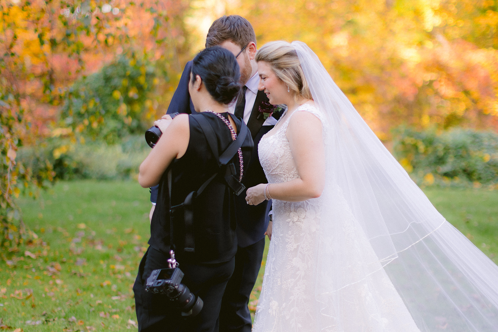 Susan Shek photographing a bride and groom among autumn leaves